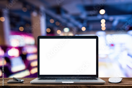 Desk Laptop with blank screen on table of coffee shop blur background