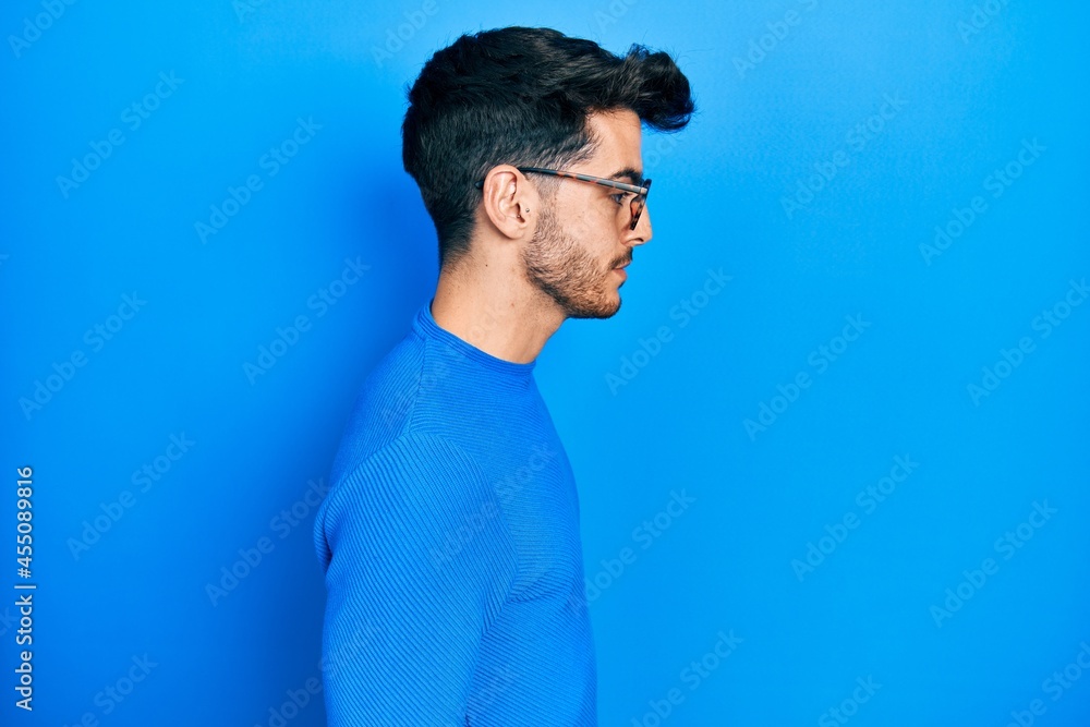 Young hispanic man wearing casual clothes and glasses looking to side, relax profile pose with natural face with confident smile.