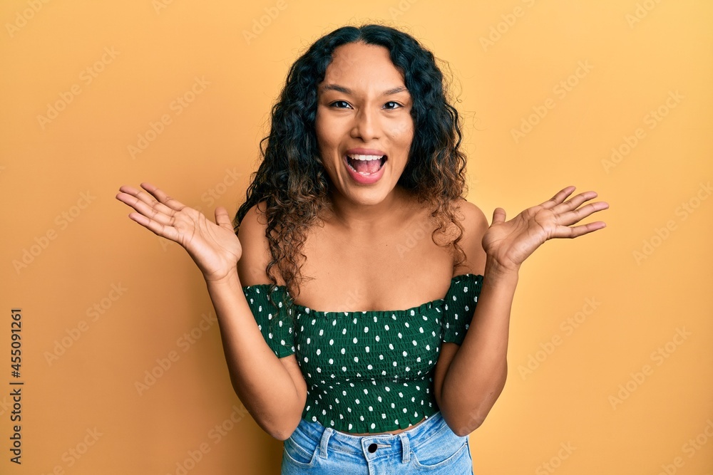 Young latin woman wearing casual clothes celebrating mad and crazy for success with arms raised and closed eyes screaming excited. winner concept Young latin woman wearing casual clothes celebrating mad and crazy for success with arms raised and closed eyes screaming excited. winner concept