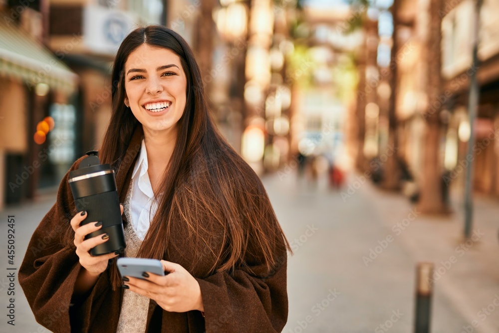 Young hispanic woman using smartphone and drinking coffee at the city. Young hispanic woman using smartphone and drinking coffee at the city.