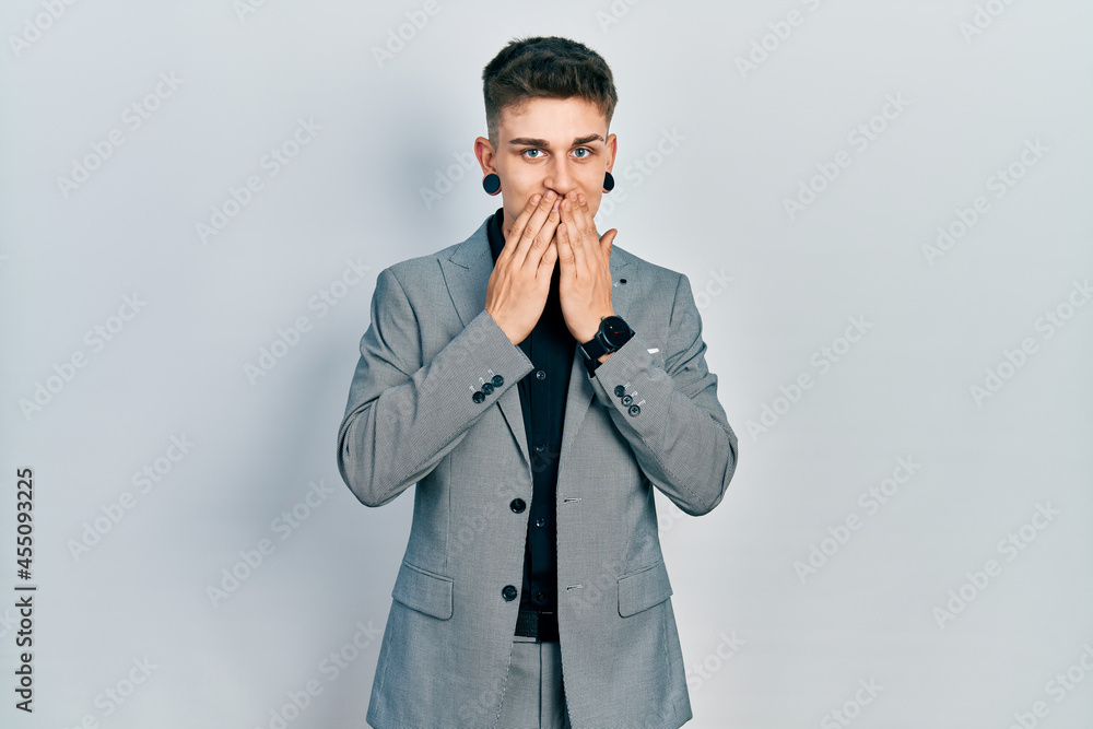 Young caucasian boy with ears dilation wearing business jacket laughing and embarrassed giggle covering mouth with hands, gossip and scandal concept Young caucasian boy with ears dilation wearing business jacket laughing and embarrassed giggle covering mouth with hands, gossip and scandal concept