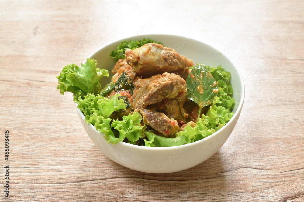 spicy fried pork bone with coconut milk curry on lettuce in bowl spicy fried pork bone with coconut milk curry on lettuce in bowl