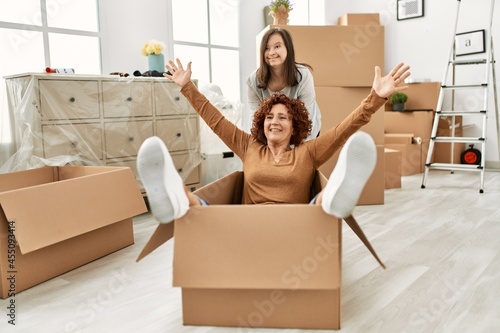 Mature mother and down syndrome daughter moving to a new home, having fun inside box © Krakenimages.com