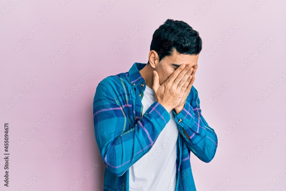 Handsome hispanic man wearing casual clothes with sad expression covering face with hands while crying. depression concept. Handsome hispanic man wearing casual clothes with sad expression covering face with hands while crying. depression concept.