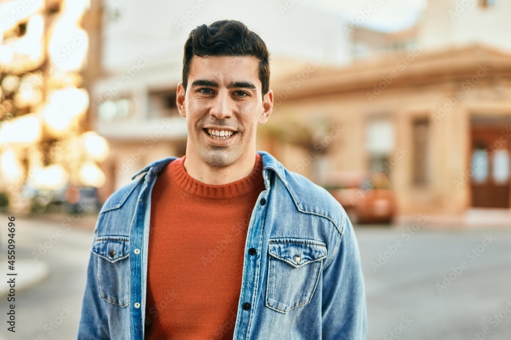 Young hispanic man smiling happy standing at the city.