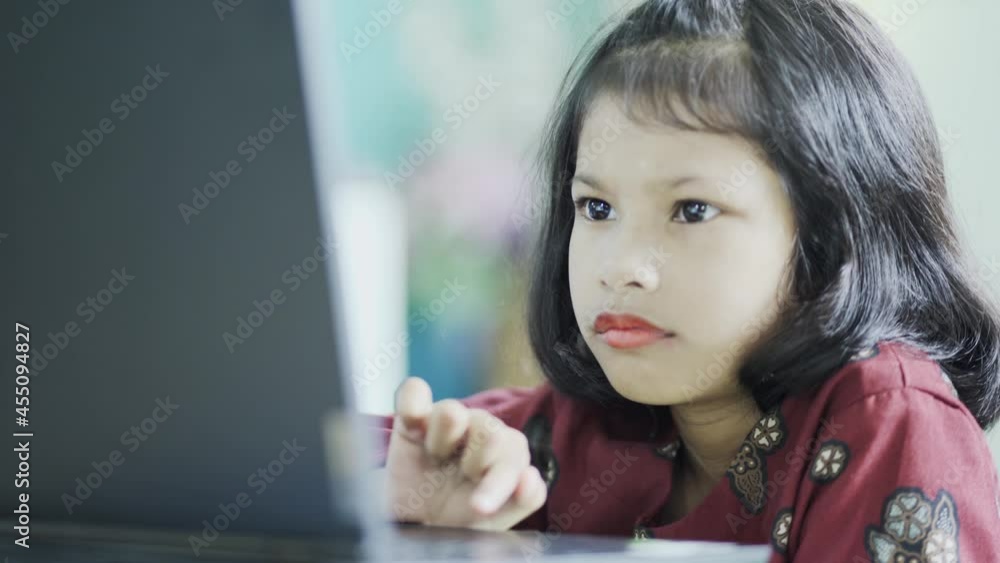 The girl at home communicates with friends on the Internet. Kids distance learning. Cute little girl using laptop at home. Education, online study, home studying, schoolgirl children lifestyle concept The girl at home communicates with friends on the Internet. Kids distance learning. Cute little girl using laptop at home. Education, online study, home studying, schoolgirl children lifestyle concept