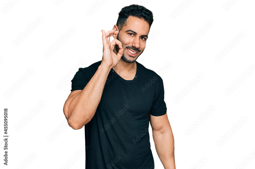 Hispanic man with beard wearing casual black t shirt smiling positive doing ok sign with hand and fingers. successful expression. Hispanic man with beard wearing casual black t shirt smiling positive doing ok sign with hand and fingers. successful expression.