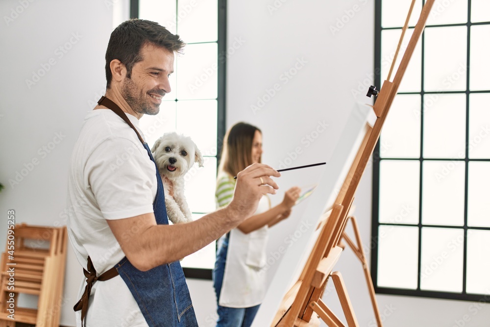 Two hispanic students smiling happy and holding dog painting at art studio. Two hispanic students smiling happy and holding dog painting at art studio.