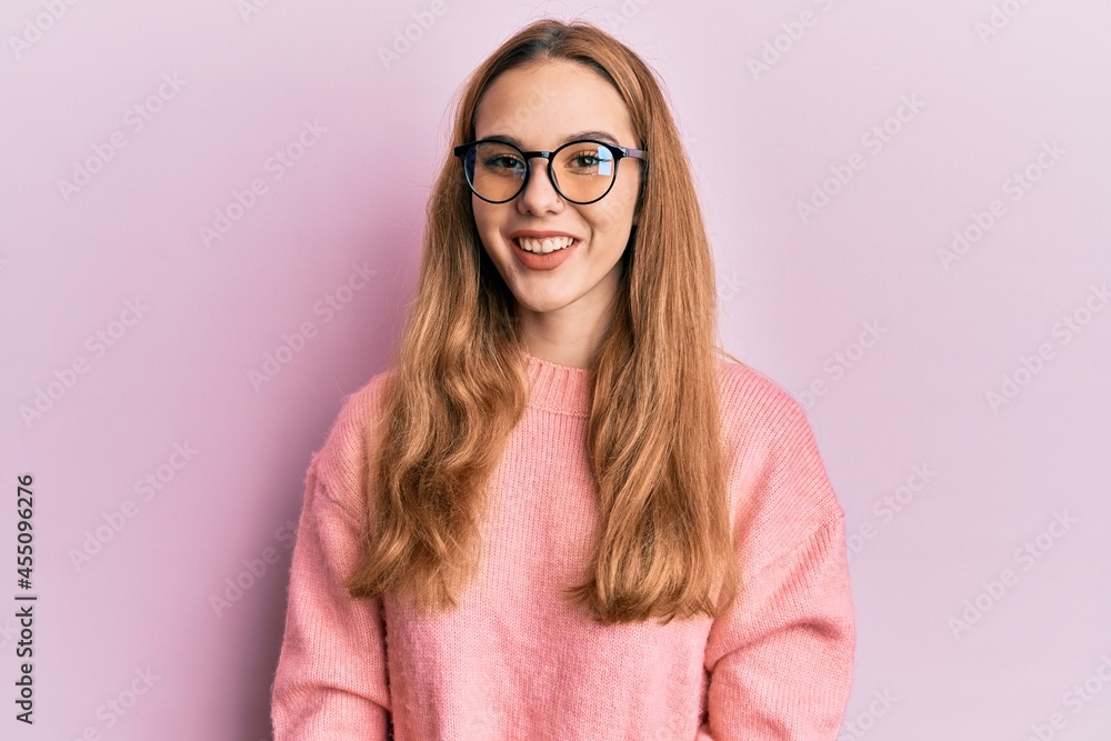 Young blonde woman wearing casual clothes and glasses with a happy and cool smile on face. lucky person. Young blonde woman wearing casual clothes and glasses with a happy and cool smile on face. lucky person.