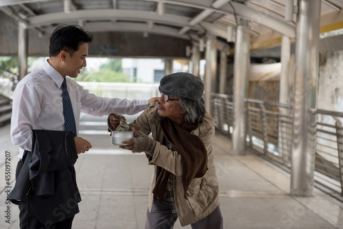 Kind asian businessman give money to old homeless