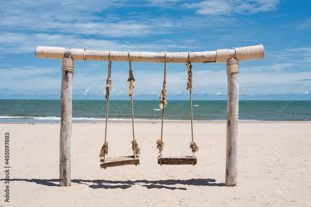 Wooden rope swing on white beach in summer