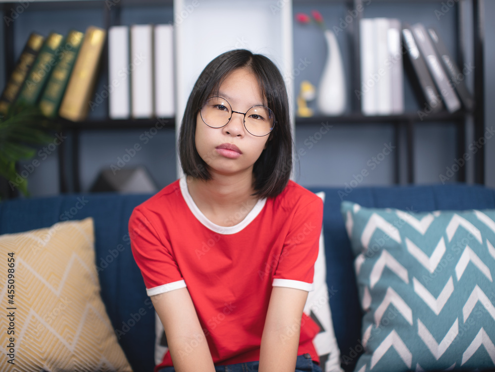 Pretty young Asian girl sitting on sofa in room with modern minimalist interior. Pretty young Asian girl sitting on sofa in room with modern minimalist interior.
