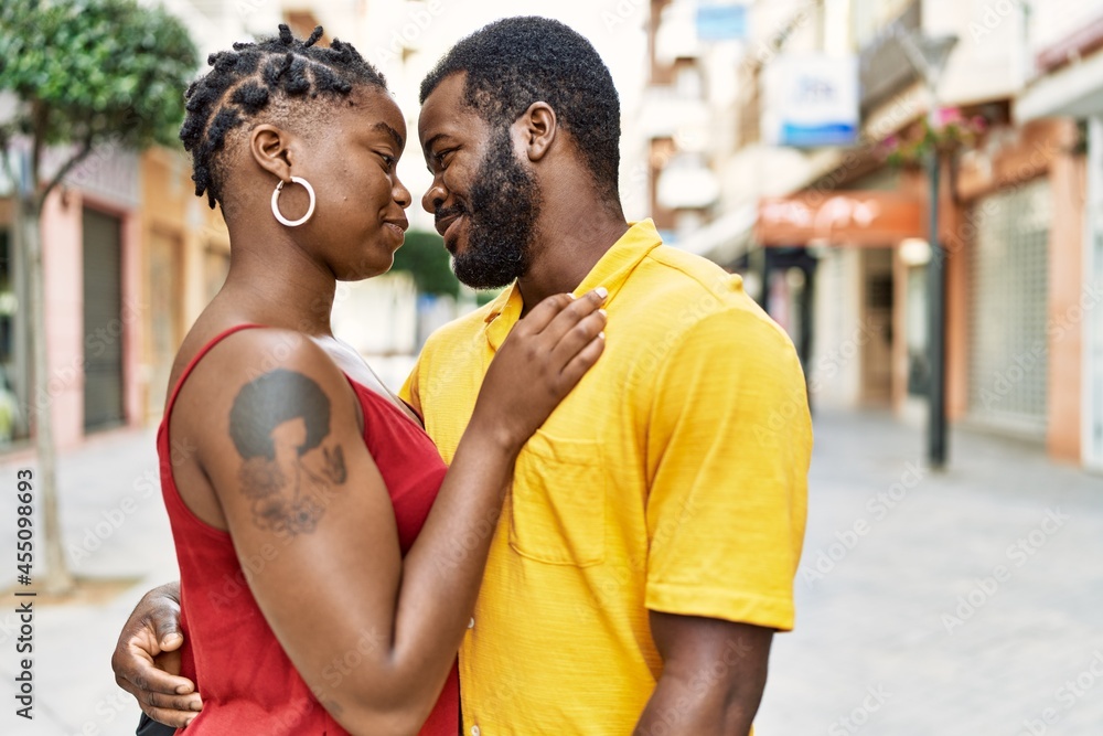 Fototapeta premium Young afircan american couple smiling happy and hugging at the city.