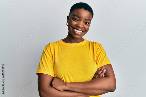 Quadro su tela Young african american woman wearing casual yellow t shirt happy face smiling with crossed arms looking at the camera