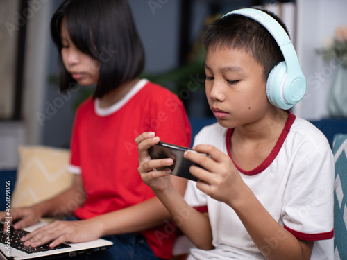 Asian boy wearing headphones and holding a phone.