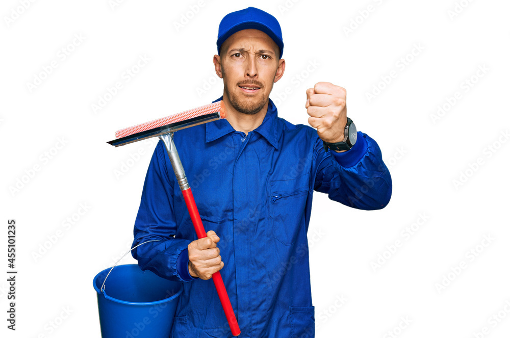 Bald man with beard wearing glass cleaner uniform and squeegee annoyed and frustrated shouting with anger, yelling crazy with anger and hand raised Bald man with beard wearing glass cleaner uniform and squeegee annoyed and frustrated shouting with anger, yelling crazy with anger and hand raised