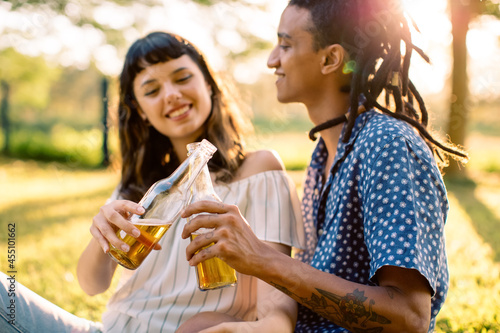 Romantic young couple toasting beer bottles in a park