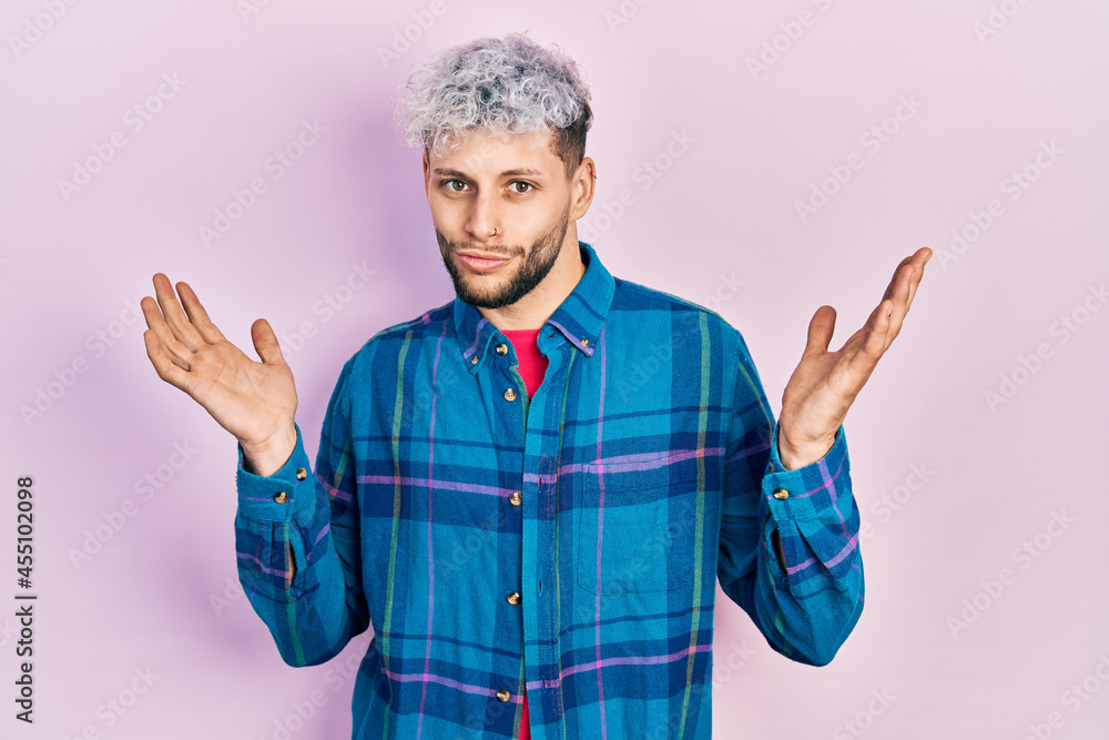 Young hispanic man with modern dyed hair wearing casual retro shirt clueless and confused with open arms, no idea and doubtful face. Young hispanic man with modern dyed hair wearing casual retro shirt clueless and confused with open arms, no idea and doubtful face.
