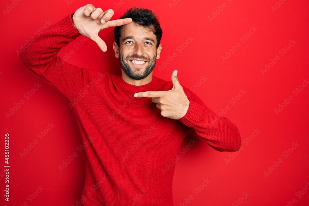 Handsome man with beard wearing casual red sweater smiling making frame with hands and fingers with happy face. creativity and photography concept. Handsome man with beard wearing casual red sweater smiling making frame with hands and fingers with happy face. creativity and photography concept.