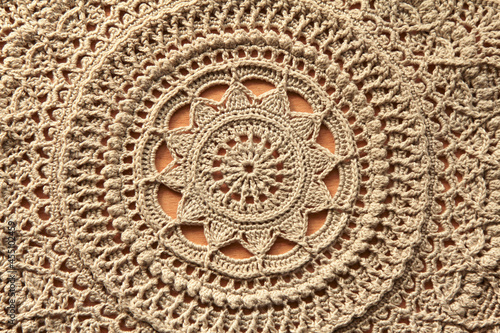 Beautiful closeup beige crochet doily on wooden background