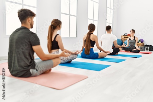 Group of young people having yoga class with personal trainer at sport center.