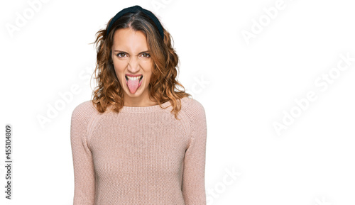 Beautiful young caucasian woman wearing casual sweater sticking tongue out happy with funny expression. emotion concept. © Krakenimages.com