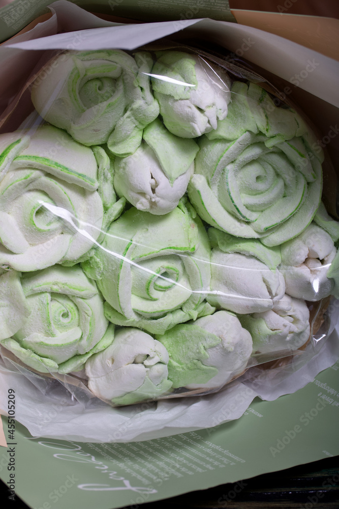 Marshmallow bouquet in paper packaging. Zephyr in the form of roses and tulips. In light green colors. Close-up shot.