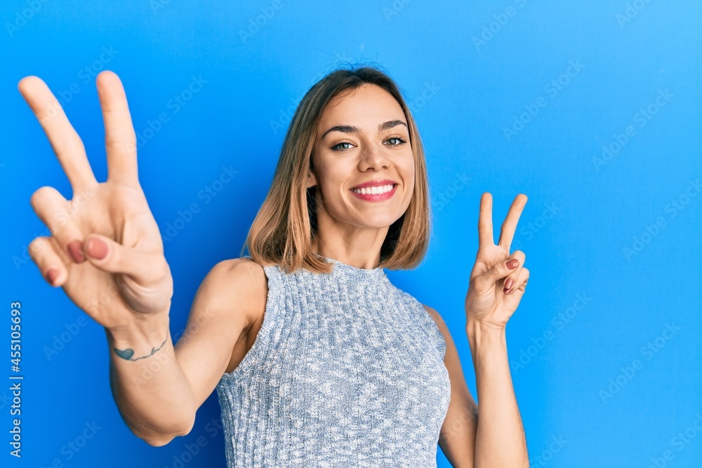 Young caucasian blonde woman wearing casual t shirt smiling looking to the camera showing fingers doing victory sign. number two. Young caucasian blonde woman wearing casual t shirt smiling looking to the camera showing fingers doing victory sign. number two.
