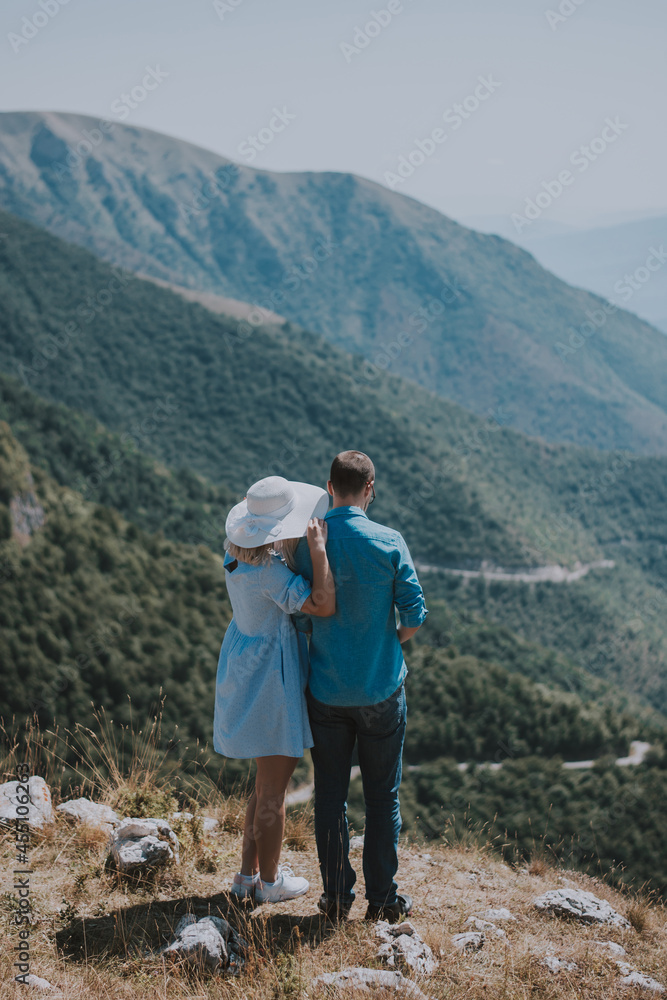 Loving couple are romantically posing against the background of the mountains. Man and woman posing on a sunny day in the mountains.