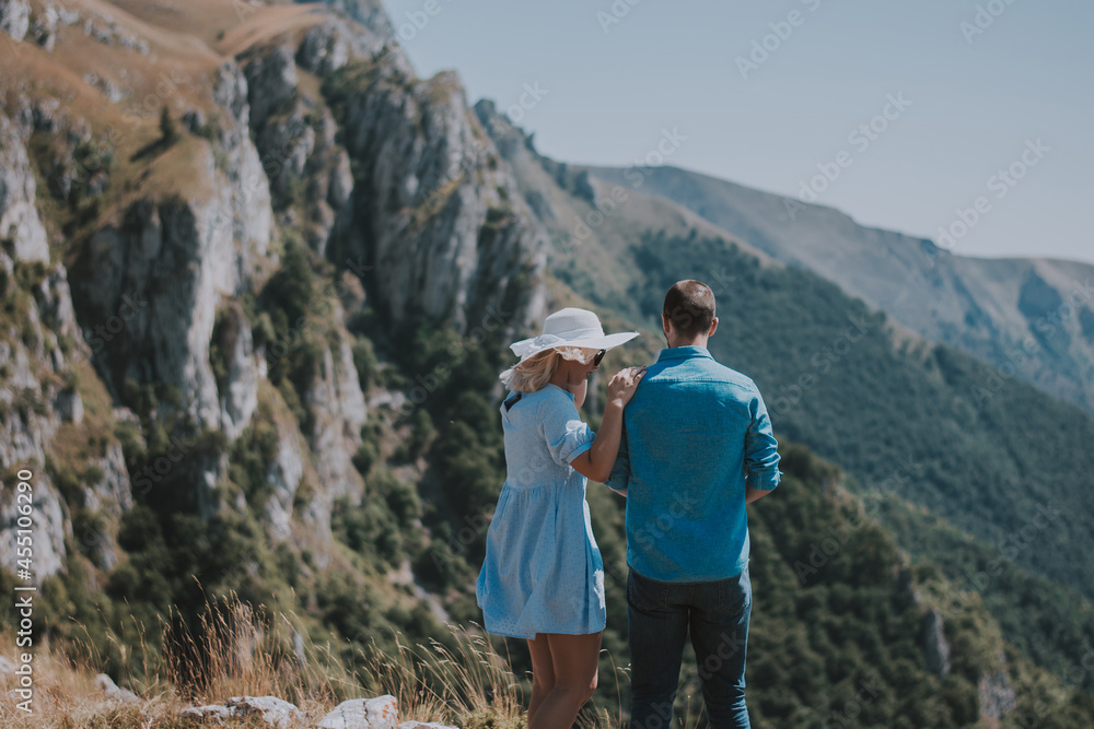 Loving couple are romantically posing against the background of the mountains. Man and woman posing on a sunny day in the mountains.