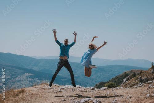 Freedom - Happy couple cheering and celebrating. Couple man and woman raising arms excited in celebration outdoors. Couple at sunset in mountain enjoying mountain top summit and success.
