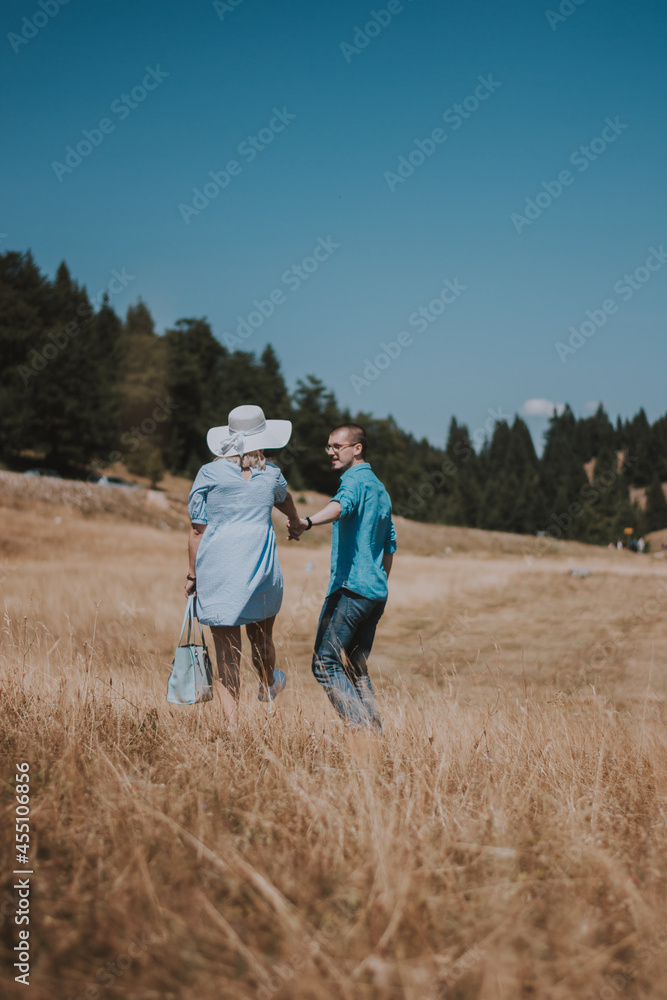 rear view of young couple walking hand in hand walking away. Man and woman walking in the mountain while holding hands. rear view of young couple walking hand in hand walking away. Man and woman walking in the mountain while holding hands.