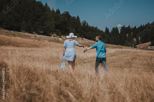 rear view of young couple walking hand in hand walking away. Man and woman walking in the mountain while holding hands.