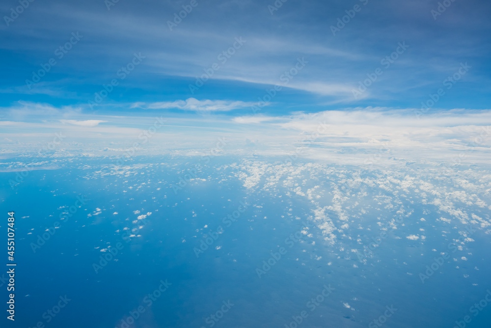 Aerial view scene of an big ocean or sea in the big ocen with white fluffy clouds and bright blue sky background.