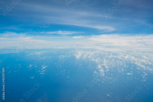Aerial view scene of an big ocean or sea in the big ocen with white fluffy clouds and bright blue sky background.