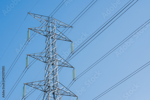 High voltage pole stand agianst white clouds and clear blue sky background with copy space