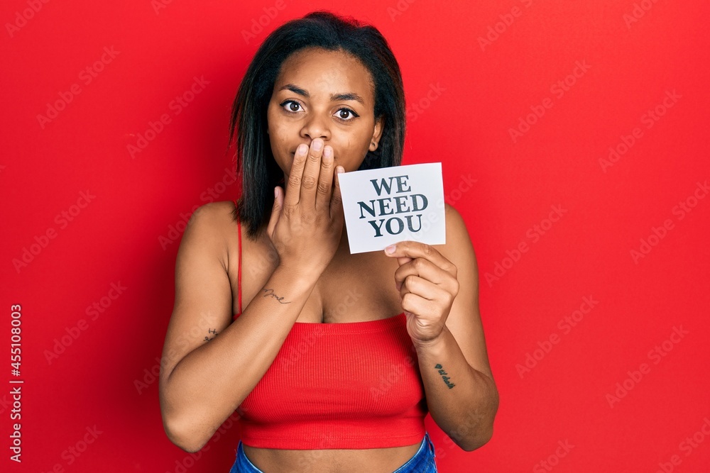 Young african american girl holding we need you paper covering mouth with hand, shocked and afraid for mistake. surprised expression Young african american girl holding we need you paper covering mouth with hand, shocked and afraid for mistake. surprised expression