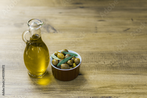 Fresh and organic green olives in a small red bowl together with olive oil in a bottle