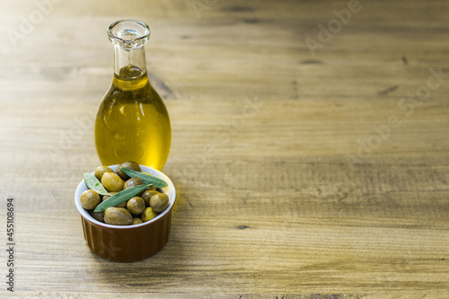 Fresh and organic green olives in a small red bowl together with olive oil in a bottle