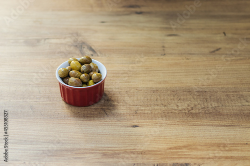 Fresh organic green olives in a red bowl on a wooden table