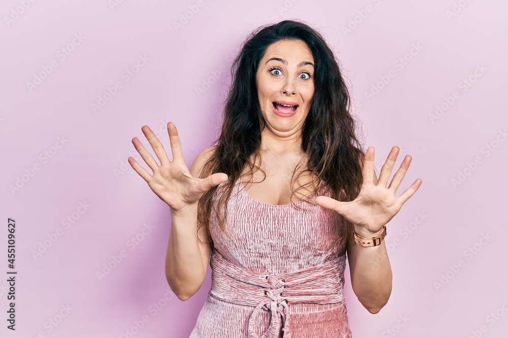 Young hispanic woman wearing casual clothes afraid and terrified with fear expression stop gesture with hands, shouting in shock. panic concept. Young hispanic woman wearing casual clothes afraid and terrified with fear expression stop gesture with hands, shouting in shock. panic concept.