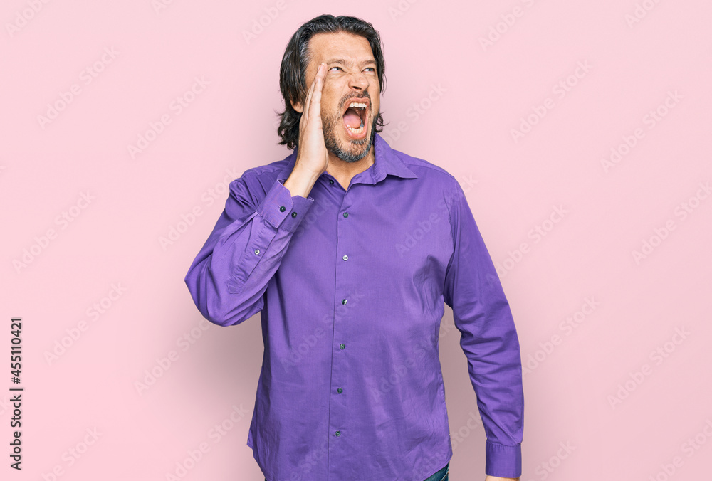 Middle age handsome man wearing business shirt shouting and screaming loud to side with hand on mouth. communication concept. Middle age handsome man wearing business shirt shouting and screaming loud to side with hand on mouth. communication concept.