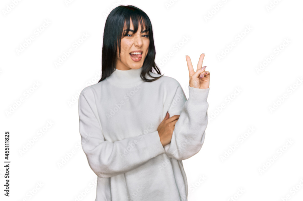 Young brunette woman with bangs wearing casual turtleneck sweater smiling with happy face winking at the camera doing victory sign. number two. Young brunette woman with bangs wearing casual turtleneck sweater smiling with happy face winking at the camera doing victory sign. number two.