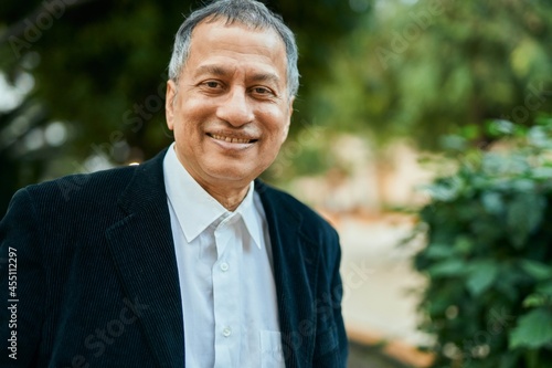 Middle age southeast asian man standing and smiling confident by the park