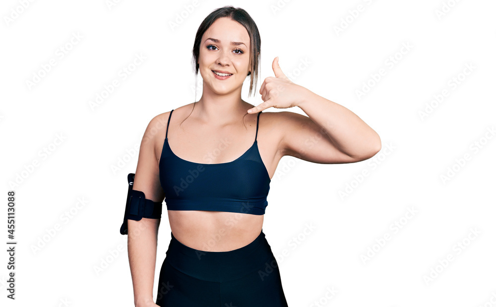 Young hispanic woman wearing sportswear smiling doing phone gesture with hand and fingers like talking on the telephone. communicating concepts. Young hispanic woman wearing sportswear smiling doing phone gesture with hand and fingers like talking on the telephone. communicating concepts.