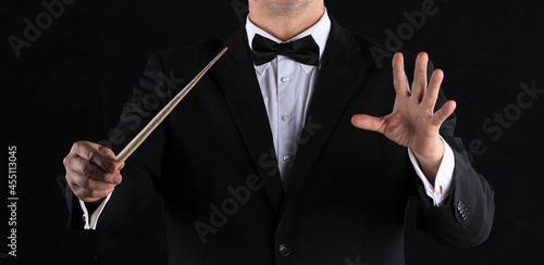 hand with conductor baton on black background
