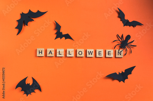 The inscription from wooden cubes and bats cut from black paper on an orange background. Halloween concept and paper decorations. Paper cut style. Flatlay, Copy Space