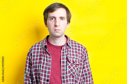 handsome angry man in red checkered shirt and looking at camera on  yellow background with copy space