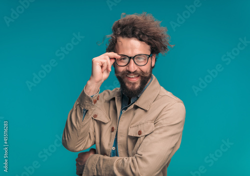 handsome young man crossing arms and adjusting eyeglasses