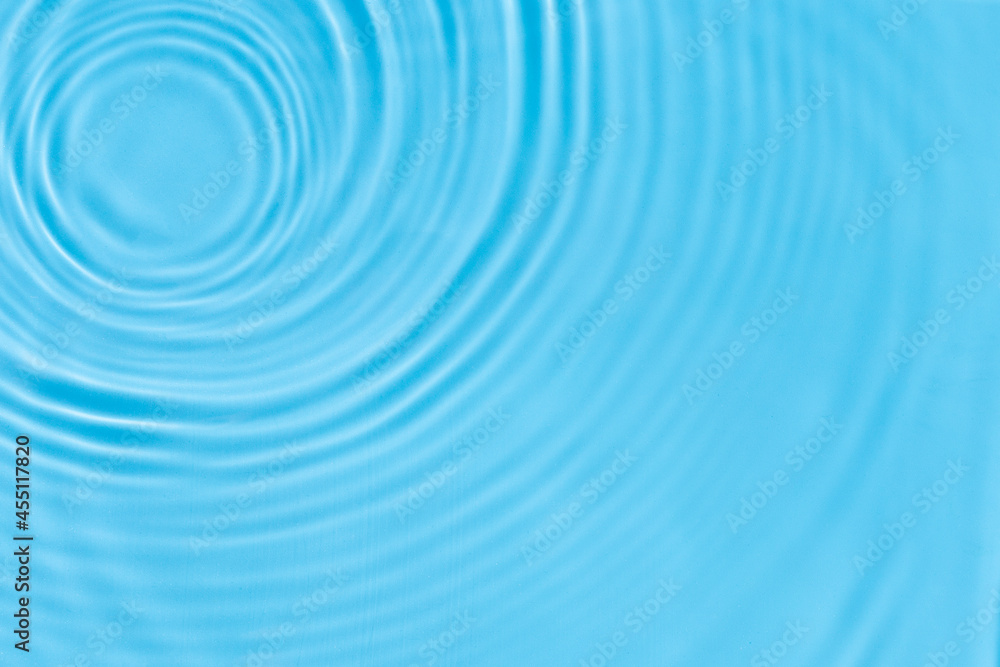 Waves from drops on blue water under the sun. Top view, flat lay Waves from drops on blue water under the sun. Top view, flat lay